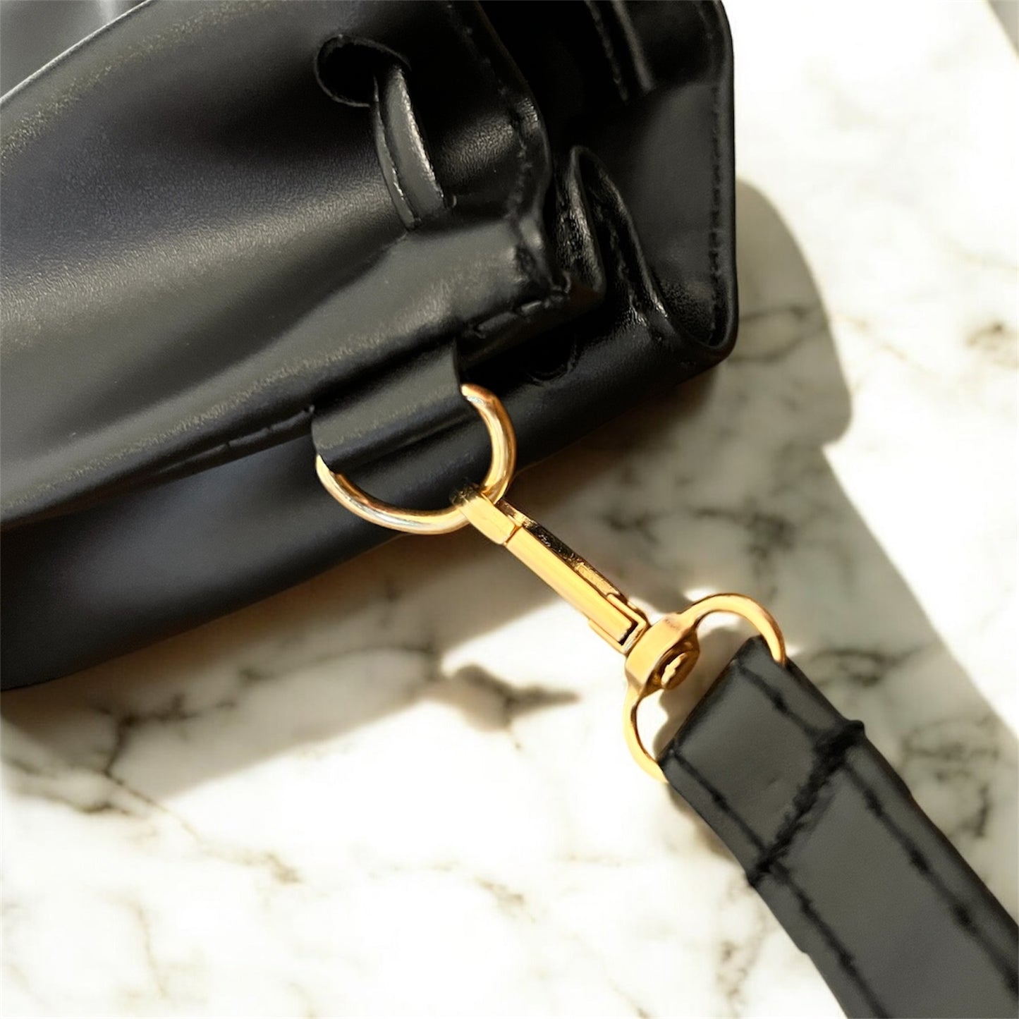 Black handbag with gold hardware on a marble surface